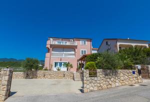 a pink house with a balcony on top of a stone wall at Villa M in Crikvenica