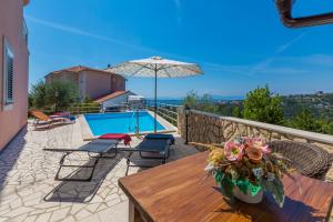a patio with a table and an umbrella and a pool at Villa M in Crikvenica
