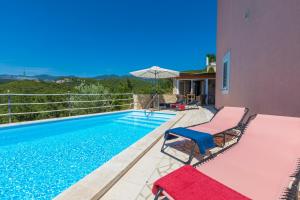 a swimming pool with two chairs and an umbrella at Villa M in Crikvenica