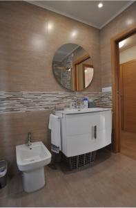 a bathroom with a sink and a toilet and a mirror at Apartamentos Playa Compostela in Vilagarcia de Arousa