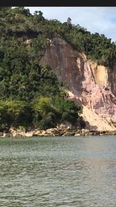 a large mountain with trees on it next to the water w obiekcie Sitio Oasis w mieście Morro de São Paulo