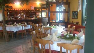 um restaurante com mesas e cadeiras brancas e um bar em Gaststätte und Pension Felsenthal em Tabarz