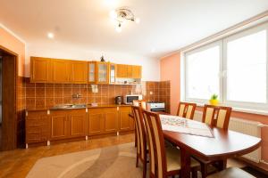 a kitchen with wooden cabinets and a table and chairs at Ubytovanie Marta Vavreková in Habovka