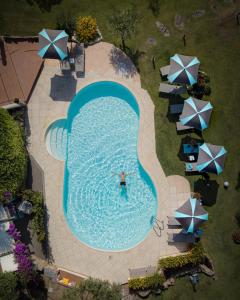 a beach with a pool, chairs, and umbrellas at Geco di Giada Art Suites - Adult Only in Porto Rotondo