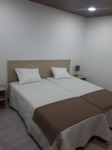 1 dormitorio con 1 cama grande con sábanas y almohadas blancas en Fonte d' Amandos, en Arganil