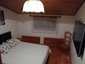 a bedroom with a white bed and a television at O Tipico in Ribadavia