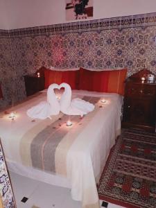 two swans are sitting on a bed with candles at Dar HAJAR in Marrakech