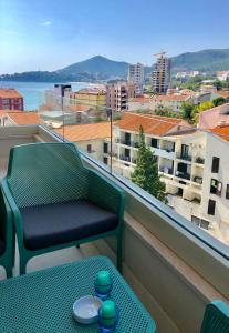 a green chair on a balcony with a view of a city at Marina Residence in Becici
