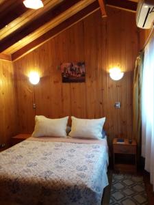 um quarto com uma cama com paredes de madeira e 2 luzes em Apart-Hotel Colonia-Königsberg ESTACIONAMIENTO Deptos Completos Ubicado En El Centro De Valdivia AIRE ACONDICIONADO em Valdivia