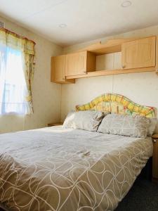 a bedroom with a bed and a window at Golden Sands Caravan Hire Ingoldmells- FREE in caravan wifi- Access included to the on site club house, sports bar, arcade, coffee shop We have beach access, a fishing lake and a laundrette in Ingoldmells