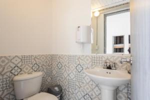 un bagno con lavandino, water e specchio di Gastón Coliving a Medellín