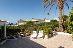dwa białe krzesła i palma na tarasie w obiekcie ASARA PLAYA 2 w mieście San Bartolomé