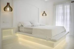 a white bedroom with a white bed and two lights at Kritamos suites in Irakleia