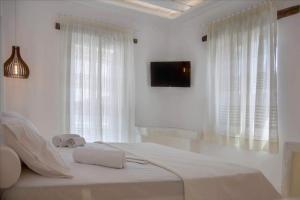 a white bedroom with a bed with two towels on it at Kritamos suites in Irakleia +9 photos