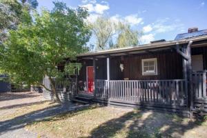a wooden house with a porch and a red door at Chum Creek Hut in Chum Creek