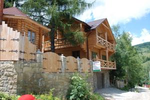 una casa de madera con una valla y una puerta en Kraevyd Hotel, en Yaremche