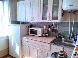 ユジノ・サハリンスクにあるApartment on Pobedy prospekt 75のキッチン(白いキャビネット、電子レンジ付きのカウンター付)