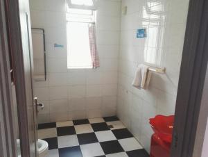 a bathroom with a red toilet and a checkered floor at LETE Hostel in Xining
