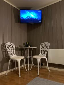 2 sillas y mesa con TV en la pared en Cozy & private room in the middle of Lofoten en Leknes