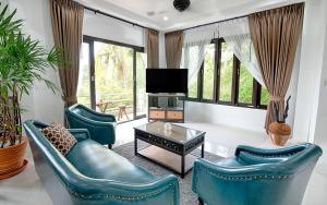Una sala de estar con dos sillas azules y un televisor. en Joy's homestay, en Ko Tao