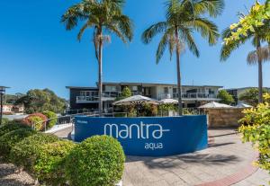 a sign in front of a building with palm trees at Mantra Nelson Bay in Nelson Bay