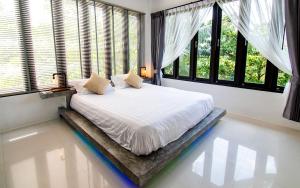 Un dormitorio con una cama con sábanas blancas y ventanas. en Joy's homestay, en Ko Tao