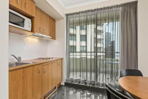 a kitchen with a sink and a window with a table at Mantra Parramatta in Sydney