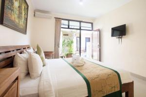 a bedroom with a bed with a television and a window at Blanjong Homestay by ecommerceloka in Sanur