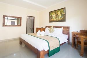 a bedroom with a large bed and a desk at Blanjong Homestay by ecommerceloka in Sanur