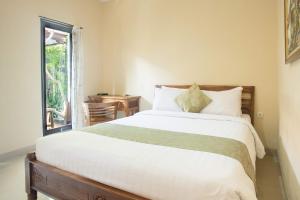 a bedroom with a large bed and a window at Blanjong Homestay by ecommerceloka in Sanur