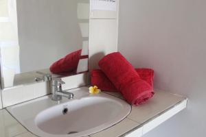 y baño con lavabo, espejo y toallas rojas. en One Homestay and Warung, en Munduk