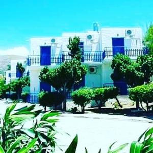 a blue and white house with trees in front of it at Aetos Beach Bungalows in Karistos