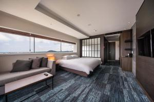 ソギポにあるGolden Tulip Jeju Seongsan Hotelのベッドとソファ付きのホテルルーム