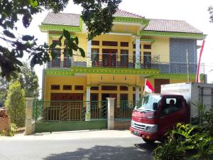 a red van parked in front of a yellow building at mas dylan homestay in Bromo