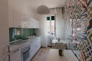 a kitchen with white cabinets and a colorful wall at Nannare' Rooms in Reggio Emilia