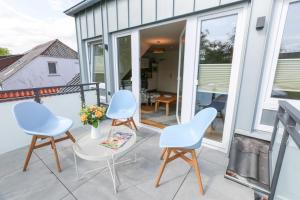 een patio met 3 stoelen, een tafel en een tv bij Boarding3 - Wohnen auf Zeit in Aurich