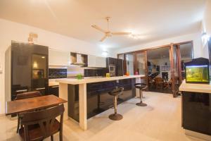 a kitchen with a bar with stools and a table at Villa Upper Dickson in Galle