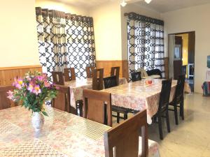 a restaurant with tables and chairs and a vase of flowers at The Hill Town Cottage in Nuwara Eliya