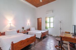 a bedroom with two beds and a desk and a tv at Five Rose Siem Reap Hostel in Siem Reap
