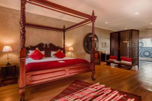 a bedroom with a canopy bed with red pillows at Singa Lodge - Lion Roars Hotels & Lodges in Port Elizabeth