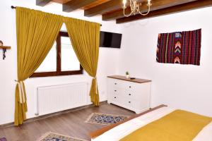 a bedroom with a bed and a window with yellow curtains at Căsuța de Poveste in Tîrgu Neamţ