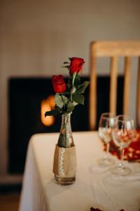 a vase with three roses on a table with wine glasses at Singa Lodge - Lion Roars Hotels & Lodges in Port Elizabeth