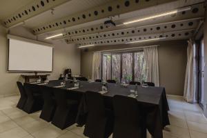 a conference room with a long table with chairs and a screen at Singa Lodge - Lion Roars Hotels & Lodges in Port Elizabeth