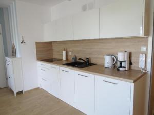 a kitchen with white cabinets and a sink at Apartament Siesta Sunny Spa in Kołobrzeg