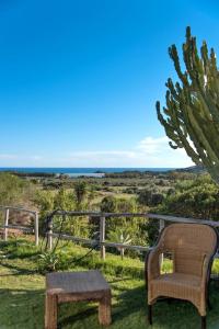 una sedia e un tavolo nell'erba con l'oceano sullo sfondo di B&B BITHIA a Chia