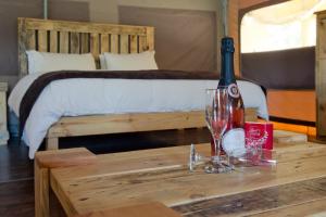 Una botella de vino en una mesa junto a la cama en African Game Lodge, en Montagu