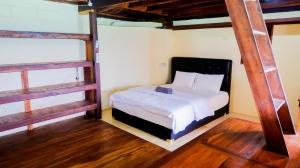 1 dormitorio con 1 cama en una habitación con suelo de madera en Phinisi Hostel Bira, en Bira
