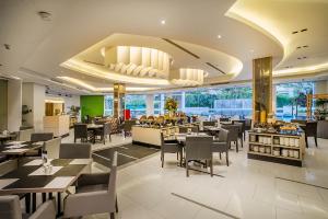 a dining room with tables and chairs in a restaurant at eL Hotel Jakarta in Jakarta