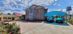 a house with two cars parked in front of it at Guest House Ugra in Barskoon