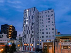 un edificio blanco alto con un letrero. en Hotel Wing International Select Kumamoto en Kumamoto